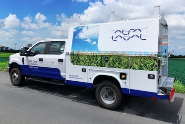 Service truck wrapped in Alfa Laval branded logo and cornfield graphics outside on side of road