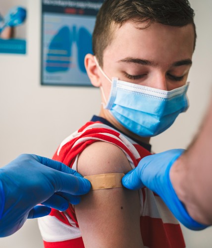 boy getting a vaccine and receiving a bandage after