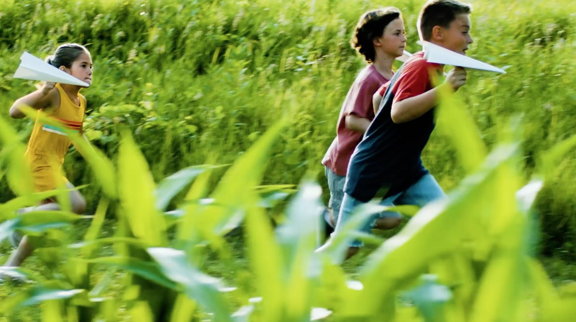 kids playing with paper airplanes in a field