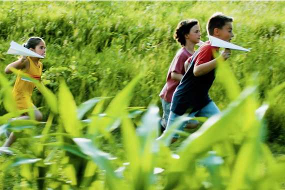 still from a tv spot of children running though a filed with paper airplanes