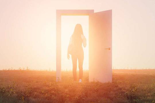 woman standing in illuminated door frame