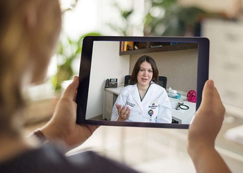 A patient viewing their tablet on which a video call with their physician is taking place.