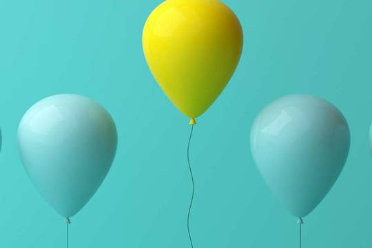 a row of blue balloons with one yellow balloon standing out