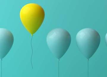 a row of blue balloons with one yellow balloon standing out