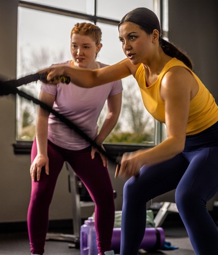 two girls working out with ropes at the gym