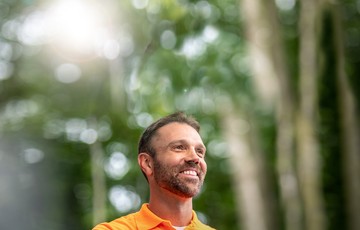 A man standing in nature surrounded by trees and sunlight