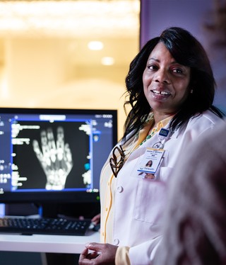 A photo taken by Core of a physician beside an x-ray image of a hand.