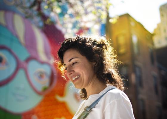 woman smiling in front of a mural