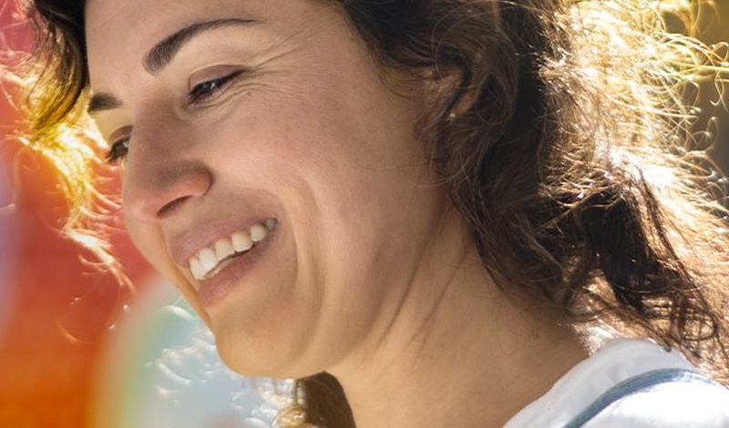 woman smiling in front of a mural