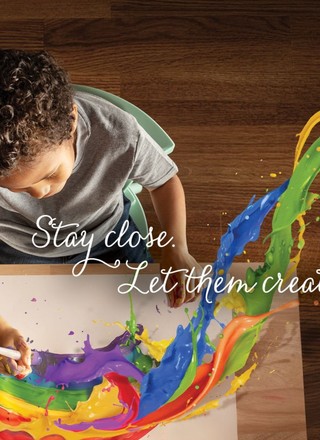 'Stay close — Let Them Create' tagline over a child creating art with paint splashing.