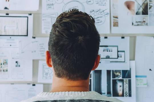 man looking at whiteboard with notes