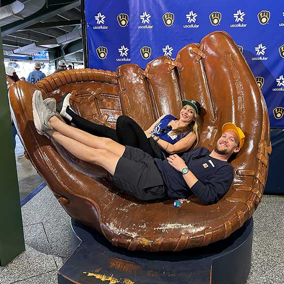 Core employees at a baseball game sitting in a giant baseball glove.