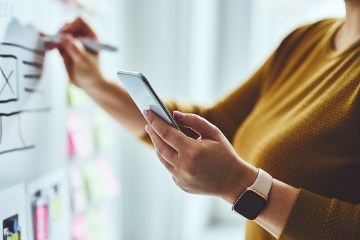 A person transferring layout ideas from their phone to a whiteboard.